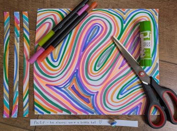 A piece of paper decorated with colourful lines and patterns in felt tip pen